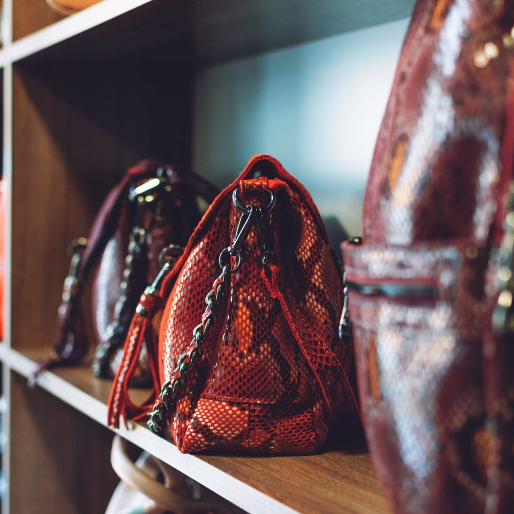 Fashion trend Snakeskin Print handbags on shelf in a store, shop. Sale, shopping, accessories concept.